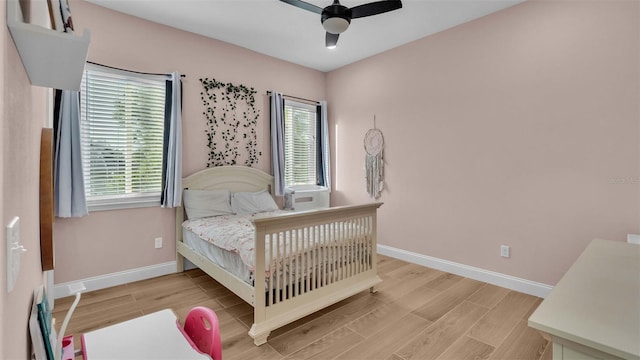 bedroom featuring light wood-type flooring, multiple windows, and ceiling fan