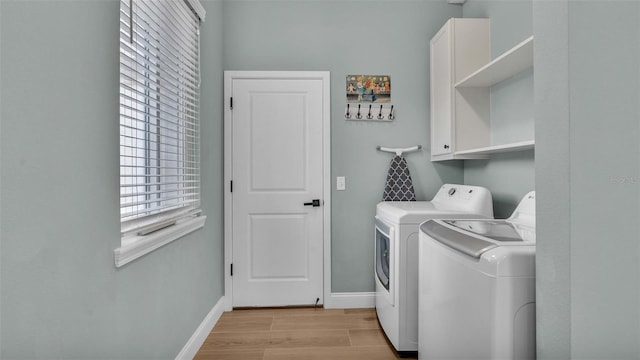 washroom featuring cabinet space, washer and dryer, light wood finished floors, and baseboards