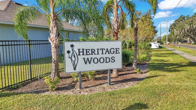 community / neighborhood sign featuring a yard and fence