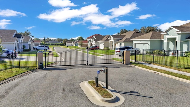 view of street with a gated entry, a residential view, curbs, sidewalks, and a gate