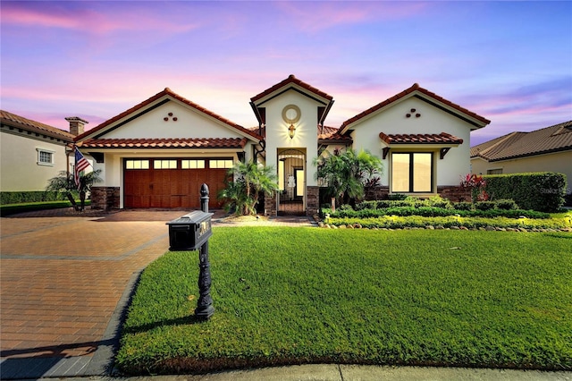 mediterranean / spanish-style house featuring a garage and a lawn