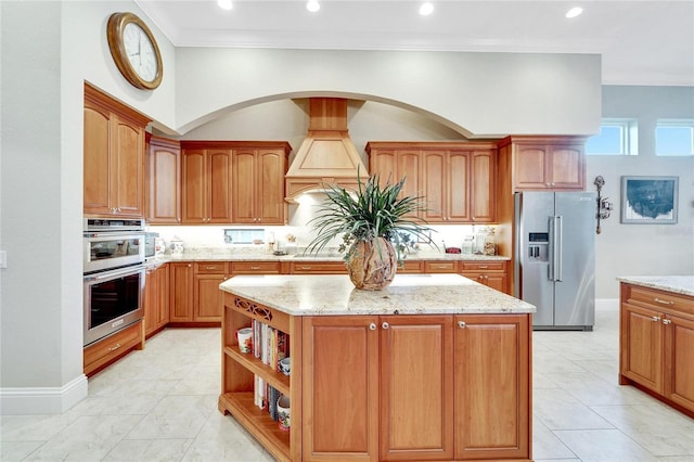 kitchen featuring light tile patterned floors, a kitchen island, light stone countertops, ornamental molding, and stainless steel appliances