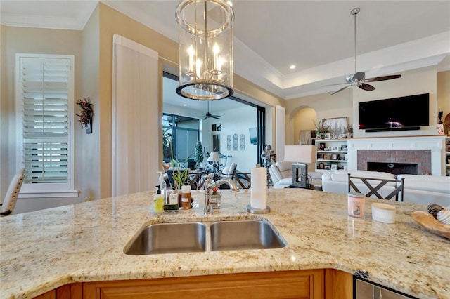 kitchen with light stone counters, sink, hanging light fixtures, and a fireplace