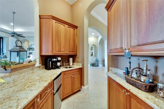 kitchen featuring light stone counters, ceiling fan, stainless steel dishwasher, crown molding, and sink