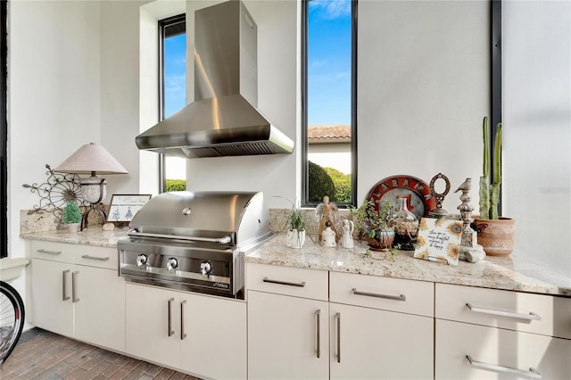 kitchen featuring a wealth of natural light, white cabinets, wall chimney range hood, and light wood-type flooring