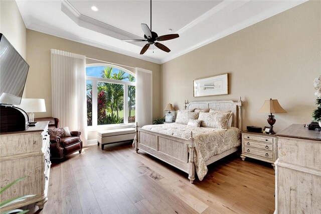 bedroom with ornamental molding, a raised ceiling, light hardwood / wood-style floors, and ceiling fan