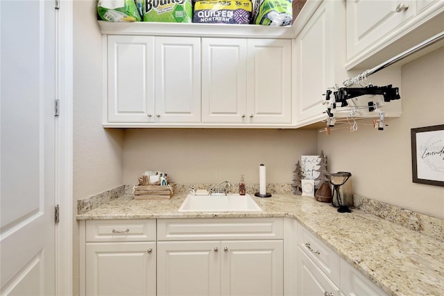 kitchen with light stone countertops, sink, and white cabinets