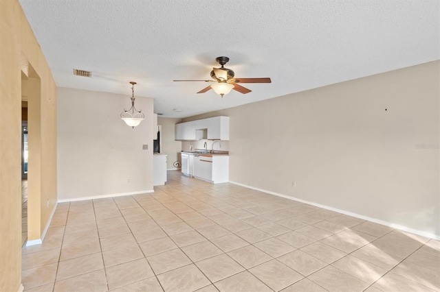 unfurnished living room featuring a textured ceiling, light tile patterned floors, and ceiling fan