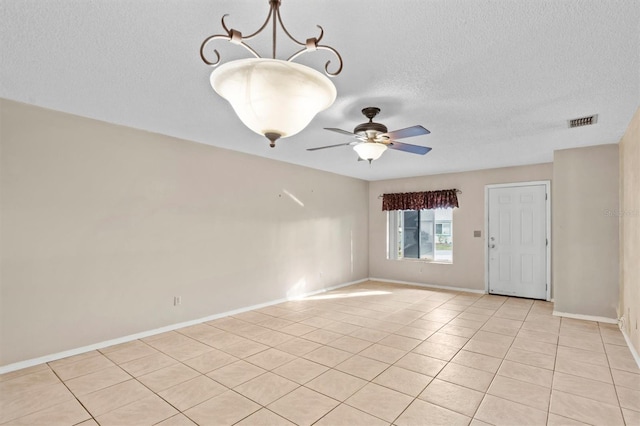 tiled spare room featuring a textured ceiling and ceiling fan