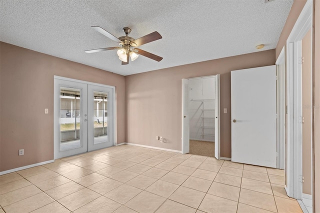 empty room with french doors, a textured ceiling, light tile patterned flooring, and ceiling fan