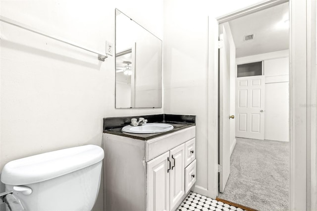 bathroom with toilet, vanity, and ceiling fan