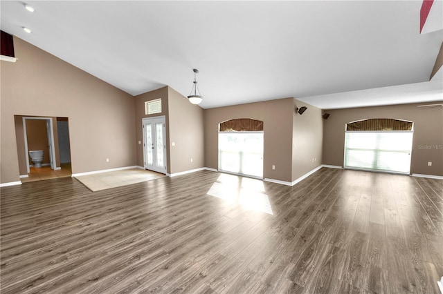 unfurnished living room with ceiling fan, high vaulted ceiling, a healthy amount of sunlight, and dark hardwood / wood-style floors