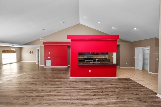 unfurnished living room with ceiling fan, hardwood / wood-style floors, high vaulted ceiling, and sink