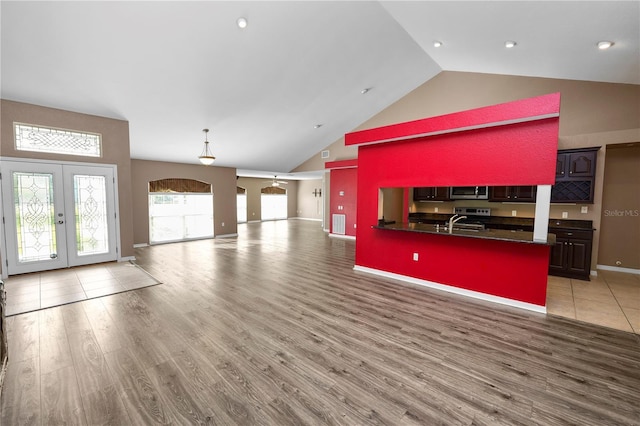 unfurnished living room featuring french doors, sink, high vaulted ceiling, and light hardwood / wood-style flooring