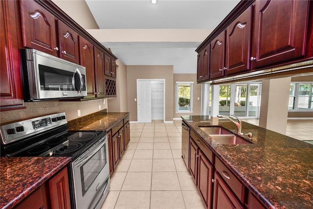 kitchen with dark stone countertops, sink, light tile patterned floors, and stainless steel appliances