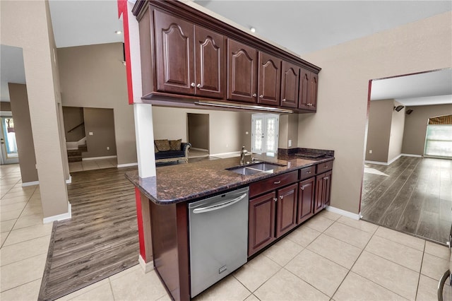 kitchen featuring kitchen peninsula, light wood-type flooring, sink, dark stone countertops, and dishwasher