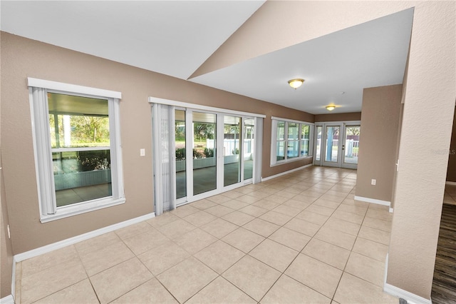 tiled empty room featuring lofted ceiling