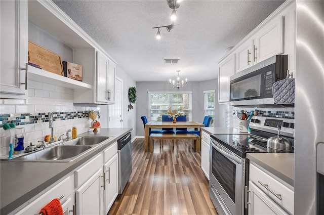 kitchen with stainless steel appliances, sink, white cabinets, a textured ceiling, and dark hardwood / wood-style flooring