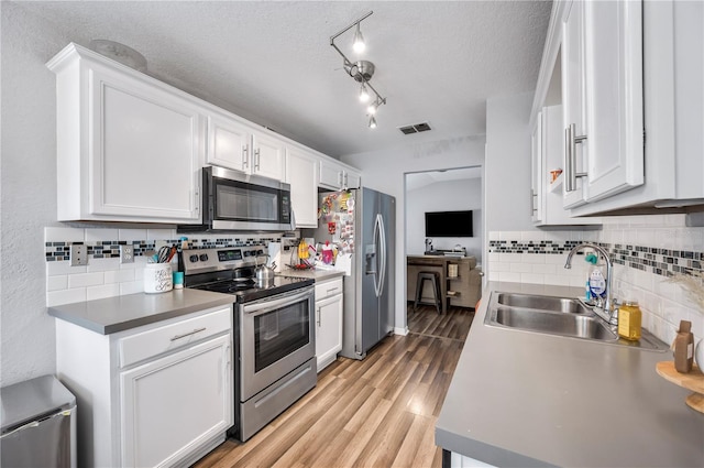 kitchen with sink, a textured ceiling, white cabinets, and stainless steel appliances