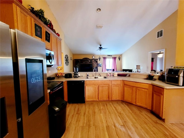 kitchen with kitchen peninsula, appliances with stainless steel finishes, light wood-type flooring, vaulted ceiling, and sink