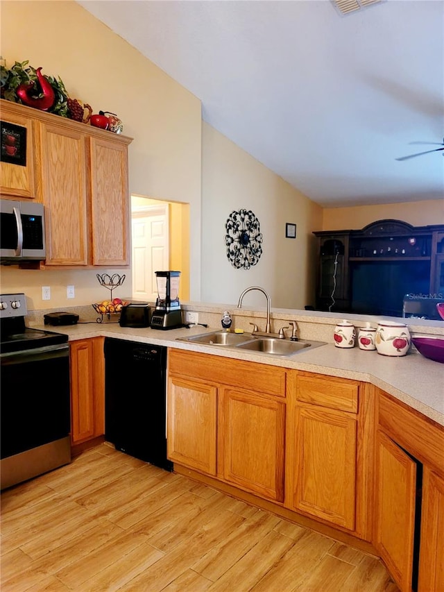 kitchen with appliances with stainless steel finishes, sink, kitchen peninsula, ceiling fan, and light hardwood / wood-style flooring