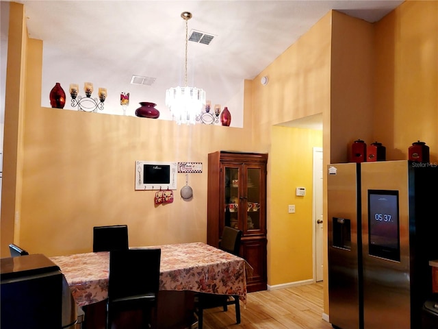 dining area with a chandelier, high vaulted ceiling, and light wood-type flooring