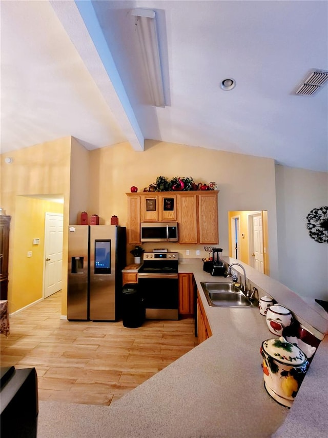 kitchen with light hardwood / wood-style floors, stainless steel appliances, sink, and vaulted ceiling with beams