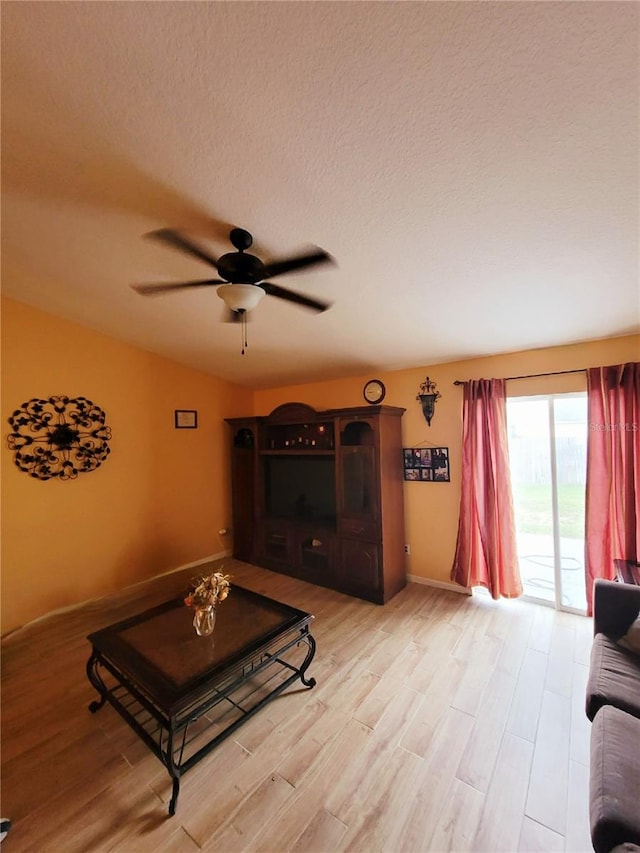 living room featuring ceiling fan, a textured ceiling, and light hardwood / wood-style floors