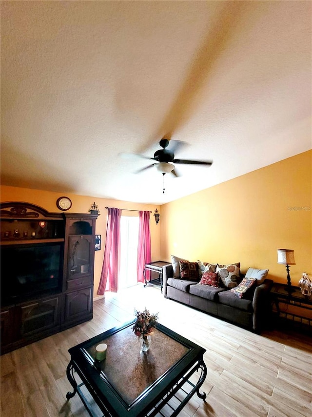 living room featuring light hardwood / wood-style floors, a textured ceiling, and ceiling fan