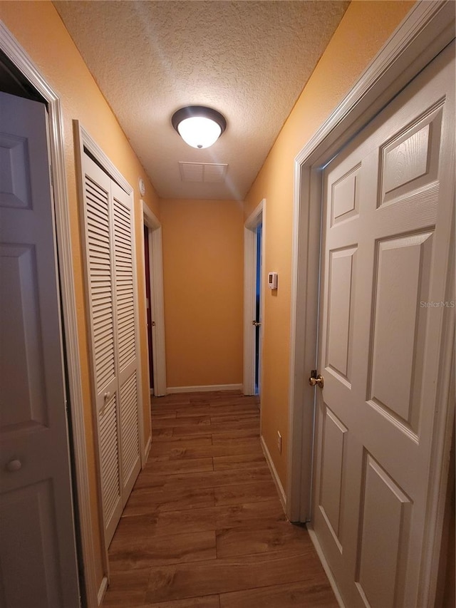 hallway featuring hardwood / wood-style floors and a textured ceiling