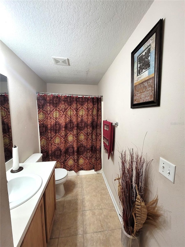 bathroom with vanity, toilet, a textured ceiling, and tile patterned flooring