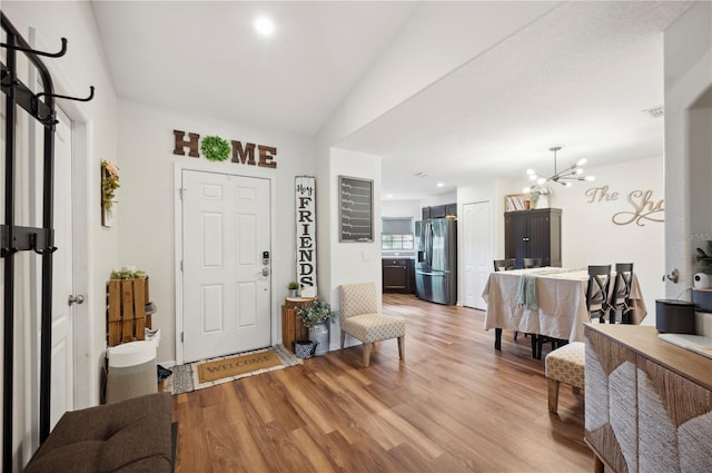 entrance foyer featuring light wood-type flooring, vaulted ceiling, and a notable chandelier