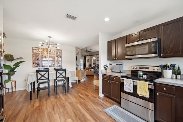 kitchen with stainless steel appliances, light hardwood / wood-style floors, ceiling fan with notable chandelier, and dark brown cabinetry