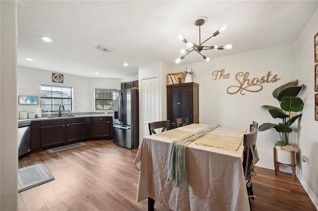 dining space with dark hardwood / wood-style flooring, sink, and a notable chandelier