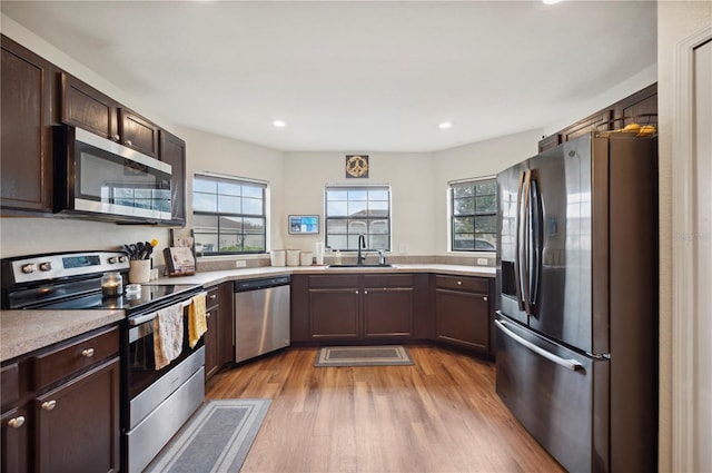 kitchen with a wealth of natural light, light wood-type flooring, appliances with stainless steel finishes, and sink