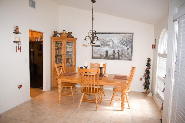 dining room featuring lofted ceiling, light tile patterned floors, and an inviting chandelier