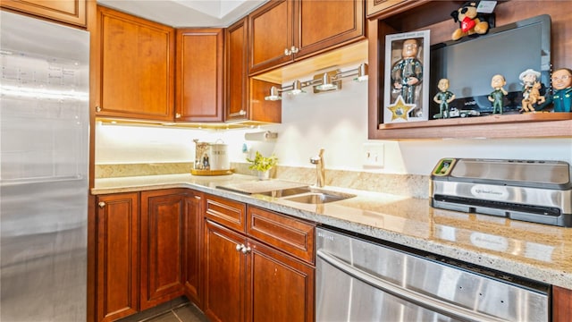 kitchen featuring sink, light stone counters, and appliances with stainless steel finishes