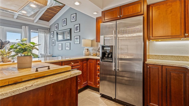 kitchen with light stone counters, vaulted ceiling with beams, stainless steel fridge, wood ceiling, and kitchen peninsula