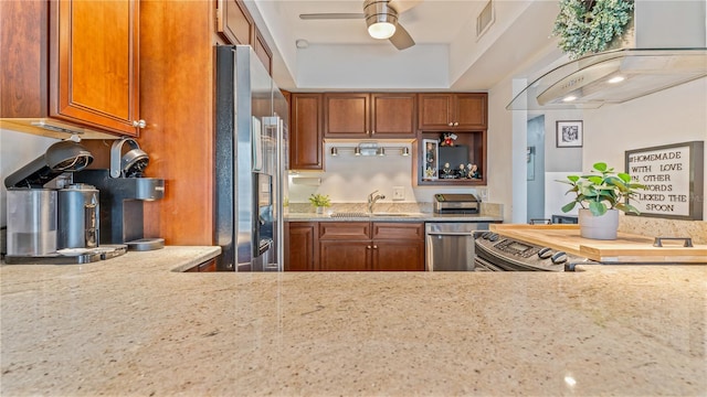 kitchen featuring stainless steel appliances, extractor fan, sink, light stone countertops, and ceiling fan