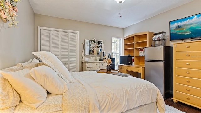 bedroom with dark wood-type flooring, stainless steel refrigerator, and a closet