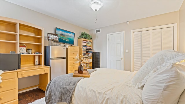 bedroom featuring dark wood-type flooring, stainless steel refrigerator, and two closets