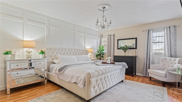 bedroom with wood-type flooring, a textured ceiling, and a notable chandelier