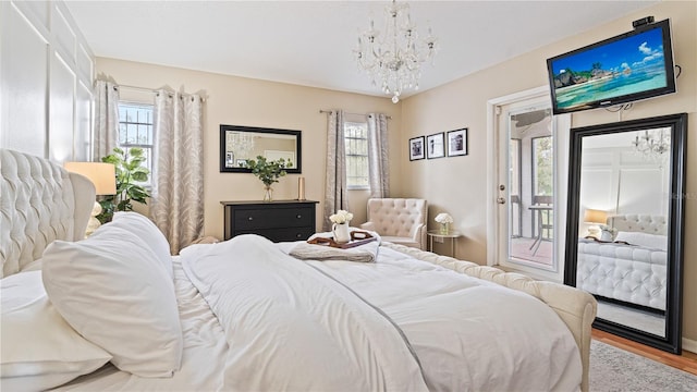 bedroom featuring access to exterior, hardwood / wood-style floors, and a notable chandelier