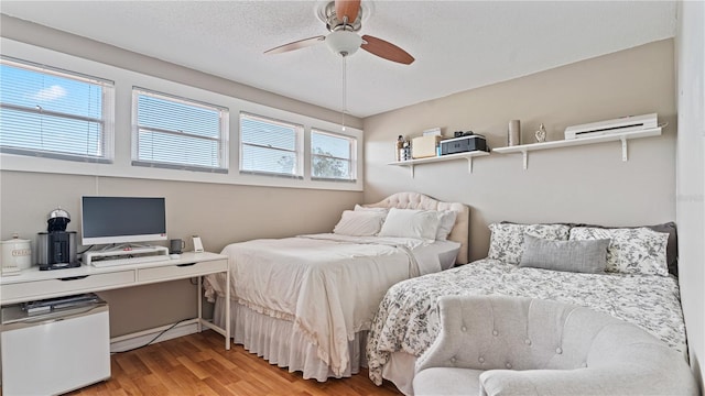 bedroom with ceiling fan, a textured ceiling, and light hardwood / wood-style flooring