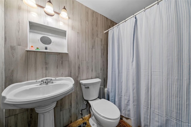 bathroom with walk in shower, toilet, and tile walls