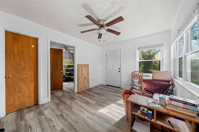 interior space featuring light hardwood / wood-style flooring, a textured ceiling, and ceiling fan