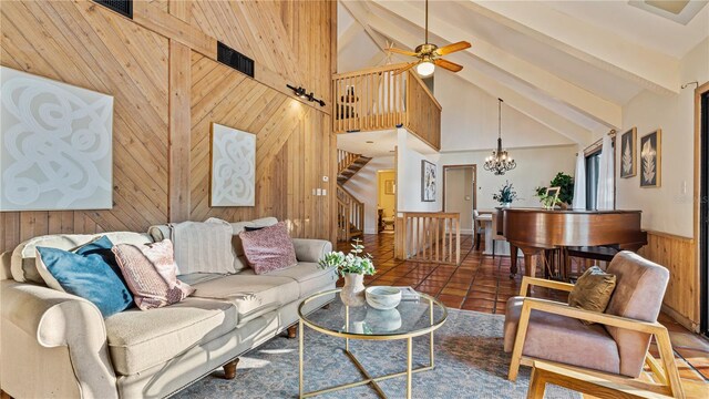 tiled living room with wood walls, beamed ceiling, ceiling fan with notable chandelier, and high vaulted ceiling