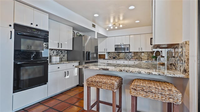 kitchen with decorative backsplash, white cabinetry, and appliances with stainless steel finishes