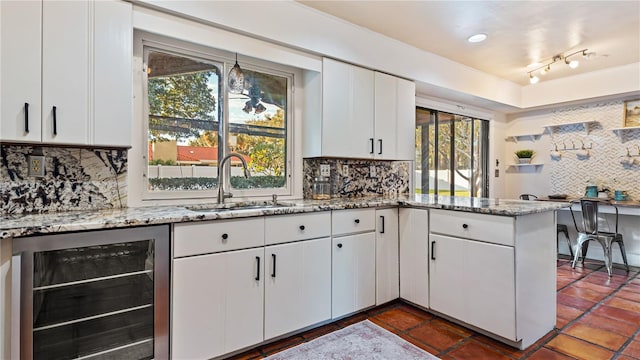 kitchen featuring white cabinets, decorative backsplash, sink, and wine cooler