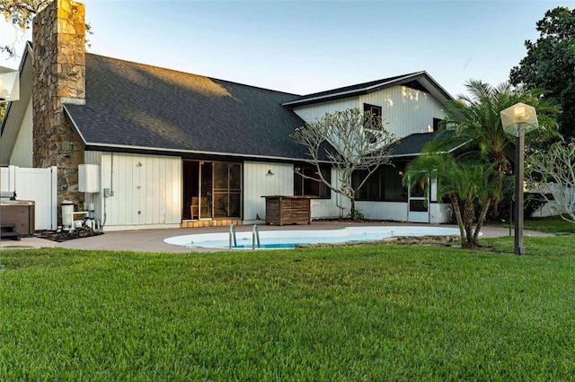 1215 Cypress Pt E, Winter Haven, FL 33884 - rear view of house featuring roof with shingles, a lawn, a chimney, and a sunroom
